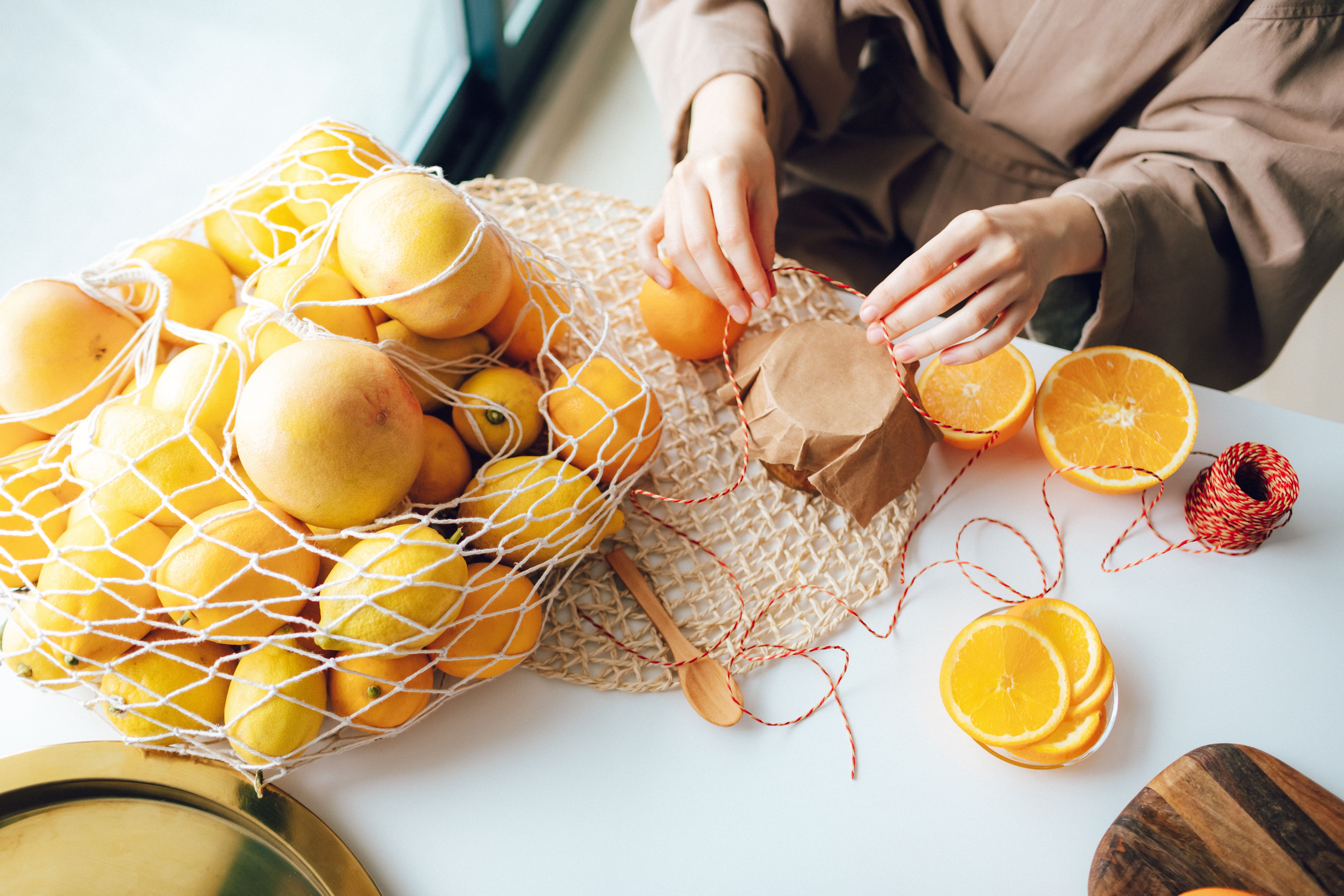 Close-up of fresh oranges, sliced and whole, with twine on a table indoors.