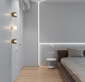 Interior of modern minimal design of bedroom with gray bed at monochrome wall with built in light