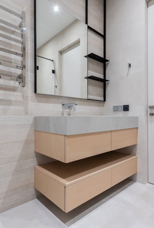 Interior of modern light restroom with sink and tap on cabinet under mirror