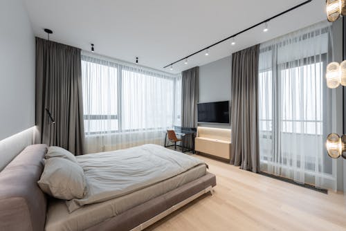 Home interior with bed next to curtains on windows