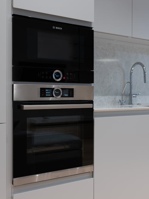 Contemporary comfortable white interior of kitchen with microwave oven and embedded electric stove
