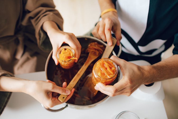 Close Up Of Woman And Man Hands Preparing Orange Jam