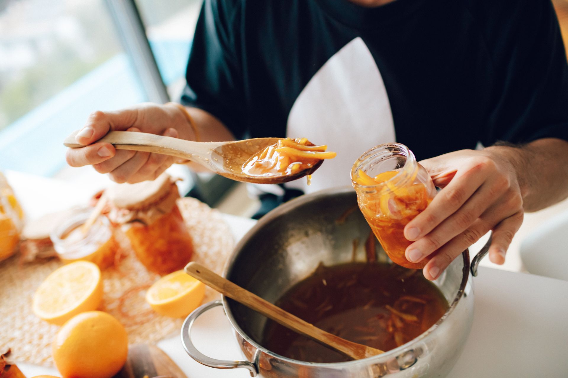 Person Holding Clear Glass Jar and Wooden Spoon