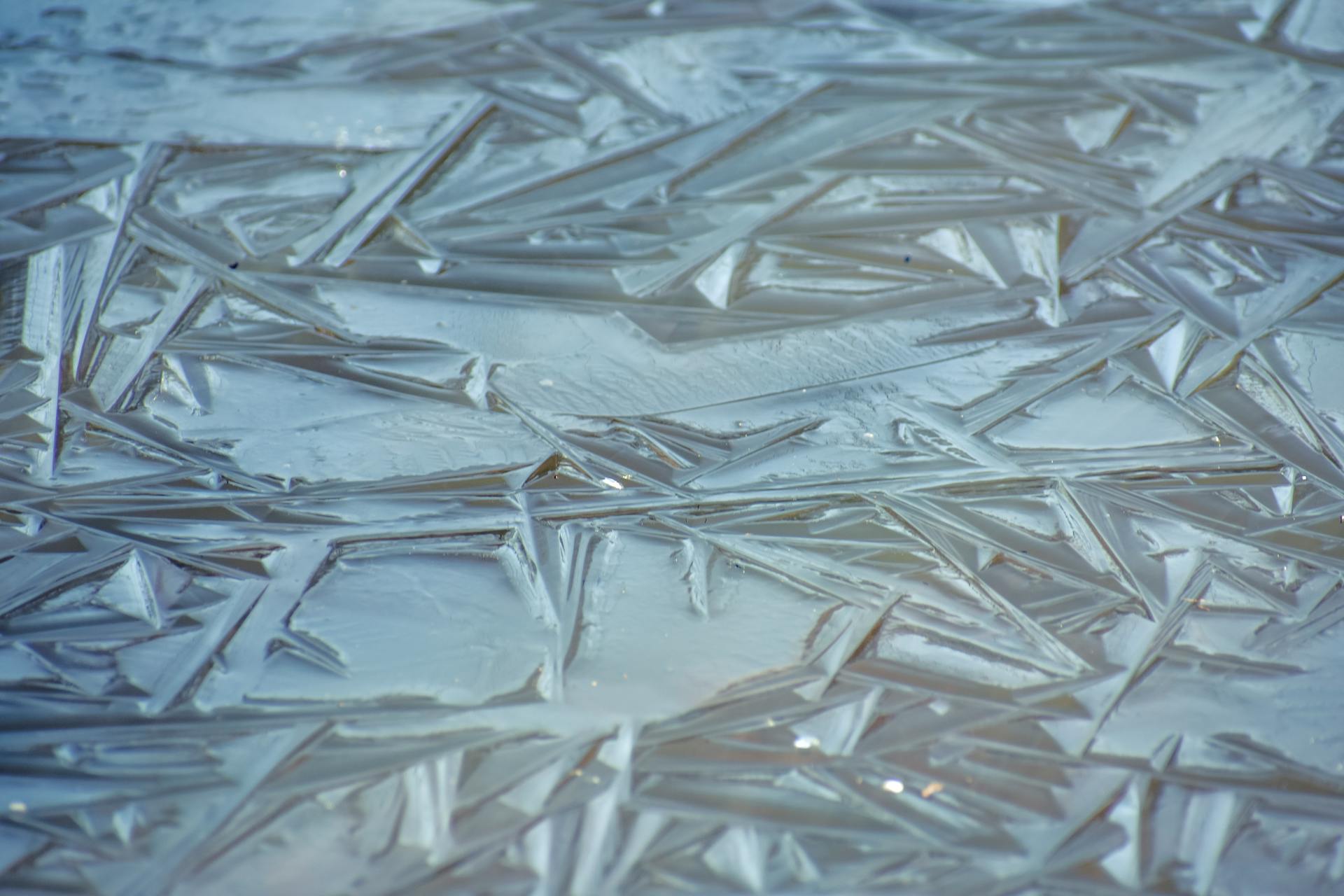 Full frame background of water in winter covered with slightly frozen clear ice with textured structure of surface