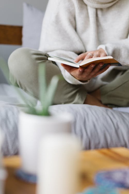 Free Faceless woman reading book on comfortable bed at home Stock Photo
