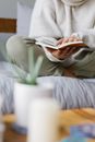 Faceless woman reading book on comfortable bed at home