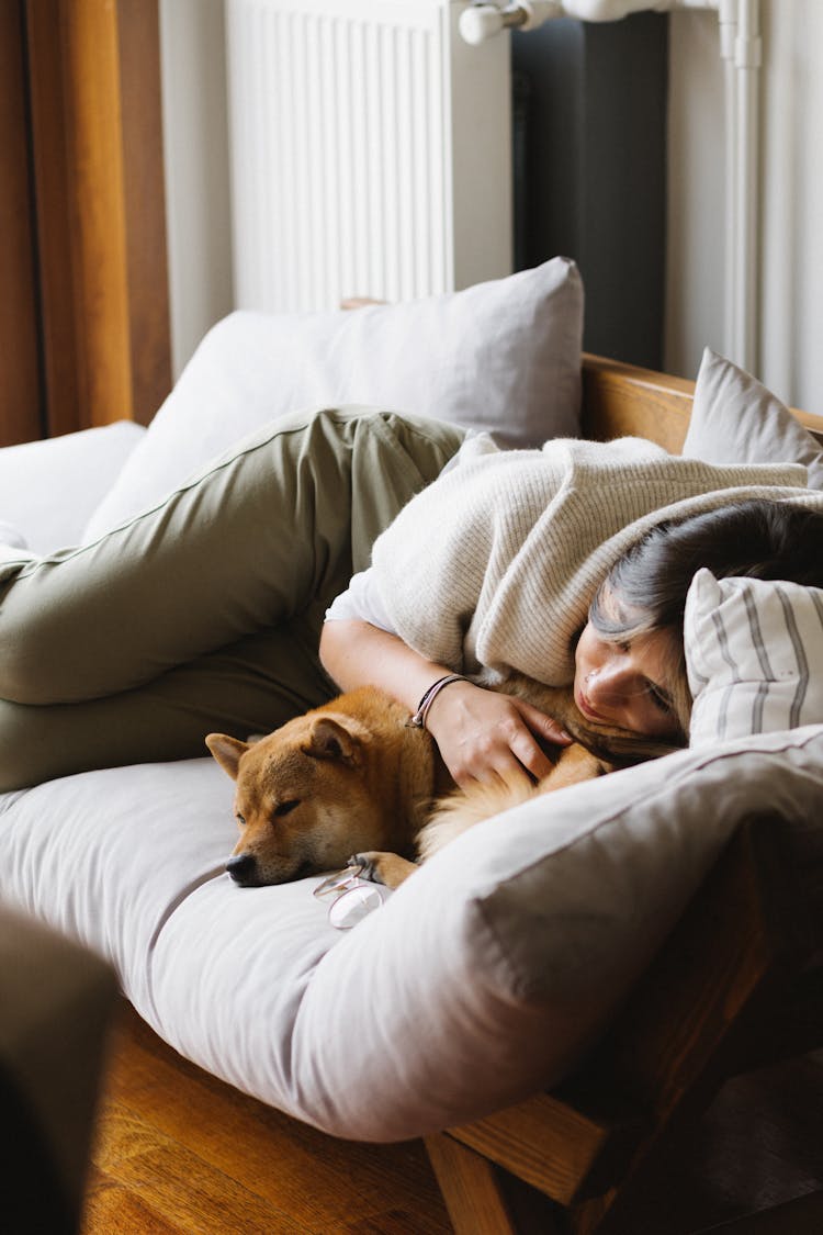 Relaxed Woman With Purebred Dog Lying On Couch