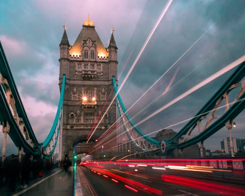 A Low Angle Shot of a Tower Bridge Under the Cloudy Sky