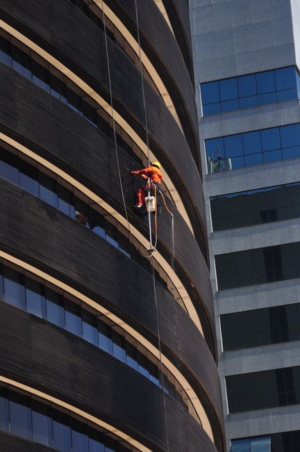 Window cleaner suspended on a high-rise building in Brasília, Brazil.