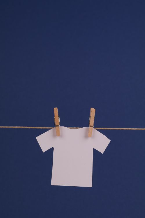 Free White paper cutout t-shirt hanging on a clothesline with wooden pegs, minimal and clean. Stock Photo