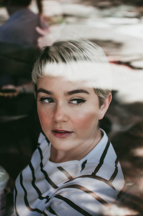 From above of young female with trendy hairstyle and makeup looking away in daytime