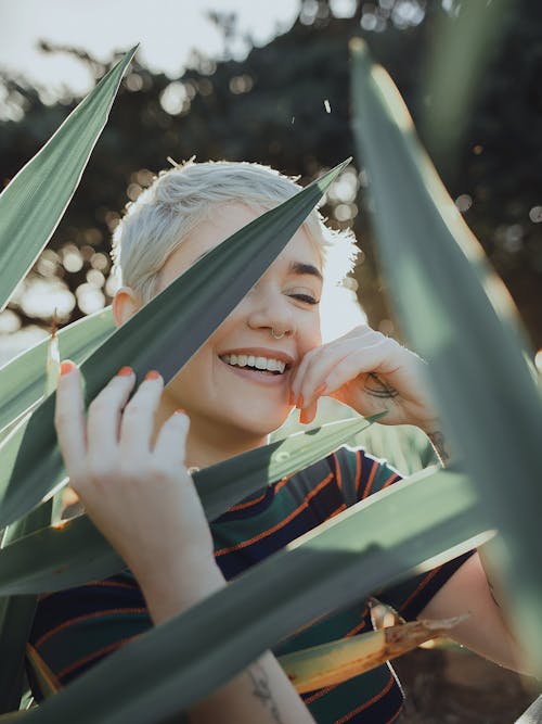 Young cheerful woman smiling among green leaves