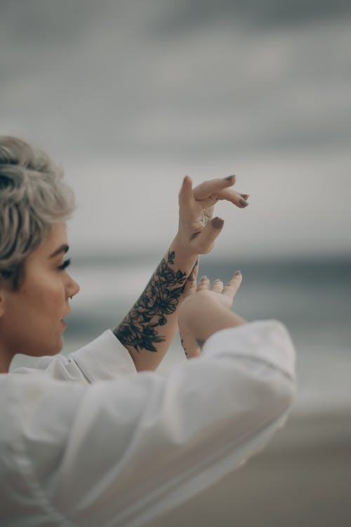 Free Side view of crop female with piercing and short dyed hair on blurred background of beach Stock Photo