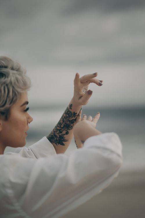 Free Side view of crop female with piercing and short dyed hair on blurred background of beach Stock Photo