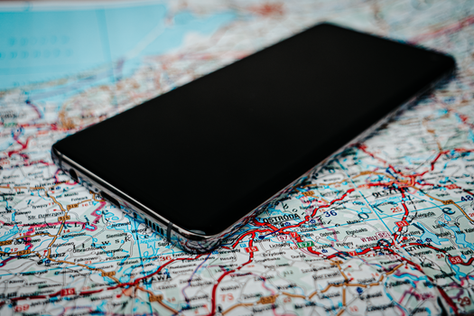 Close-up of a smartphone placed on a detailed road map of Poland, emphasizing travel and technology.