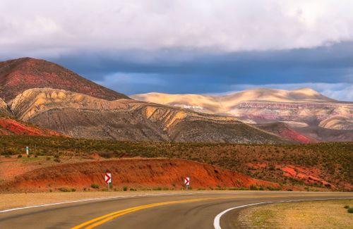 Free Breathtaking view of a winding highway through vibrant multicolored mountains under a dramatic sky. Stock Photo