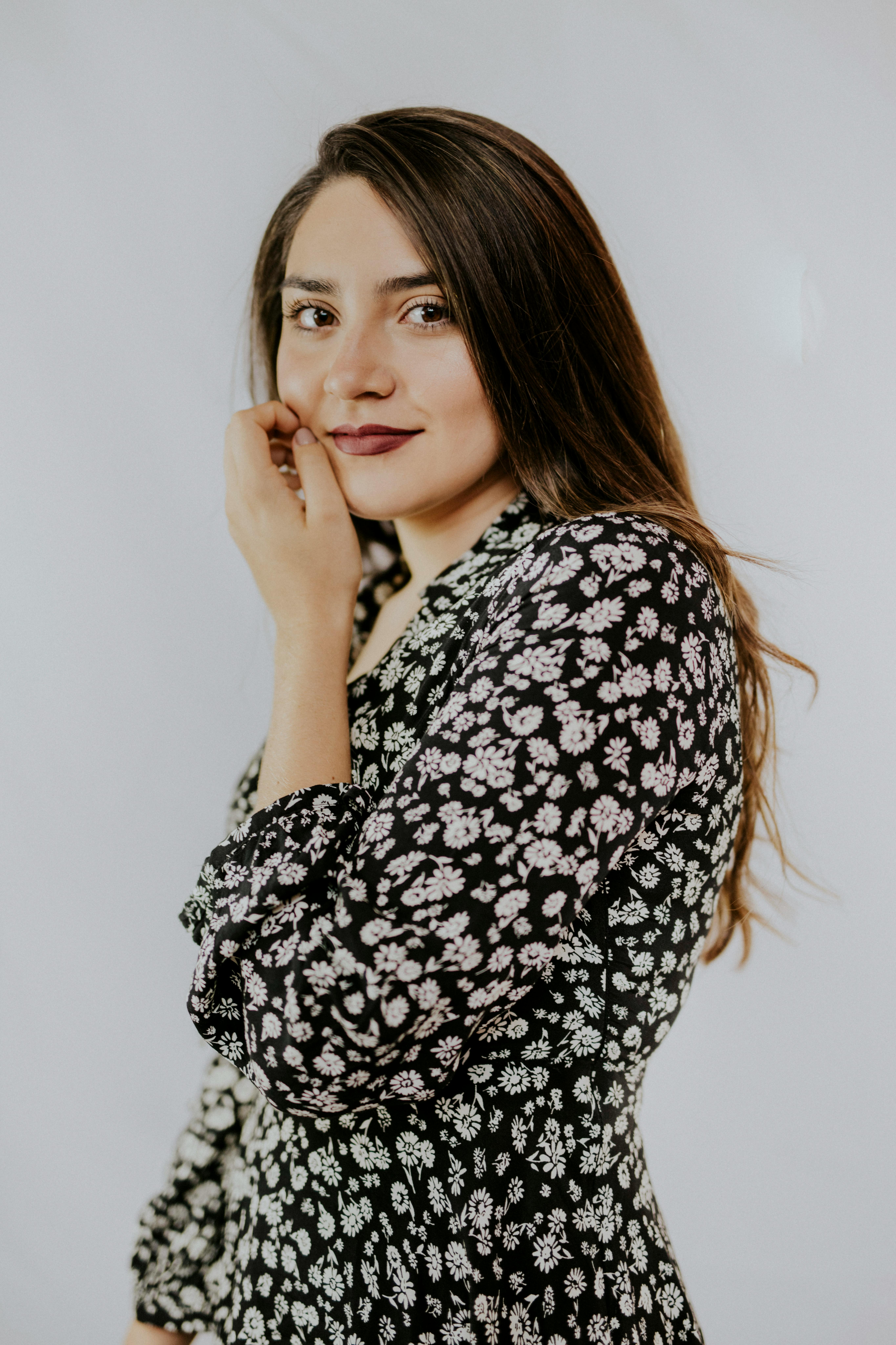 Portrait of a smiling woman posing with hand on chin in studio setting.