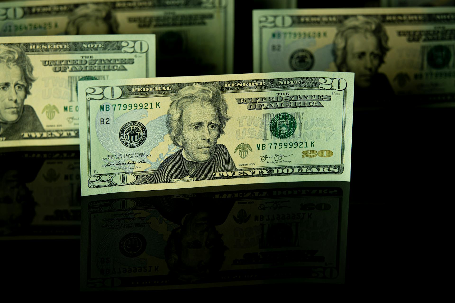 Detailed close-up of US twenty dollar bills displayed against a dark backdrop, showcasing American currency.