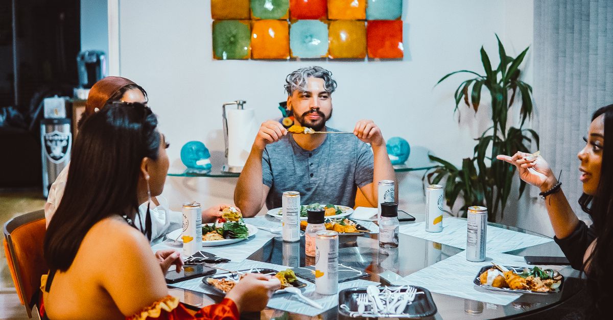 Gen Z friends laughing at a casual dinner table splitting bill