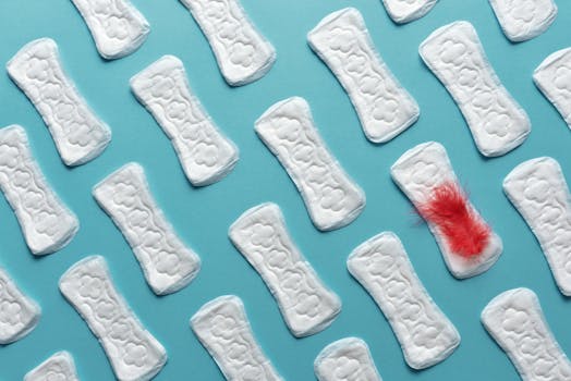 Sanitary pads arranged on blue surface with red feather accent.