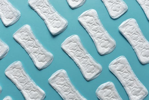 Flatlay showing multiple sanitary pads on a blue surface, emphasizing menstrual hygiene.