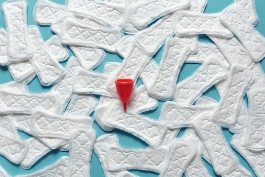 Top view of menstrual products including pads and cup on a blue background.