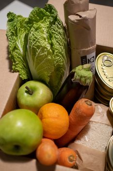 A collection of fresh fruits, vegetables, canned goods, and grains in a cardboard box.