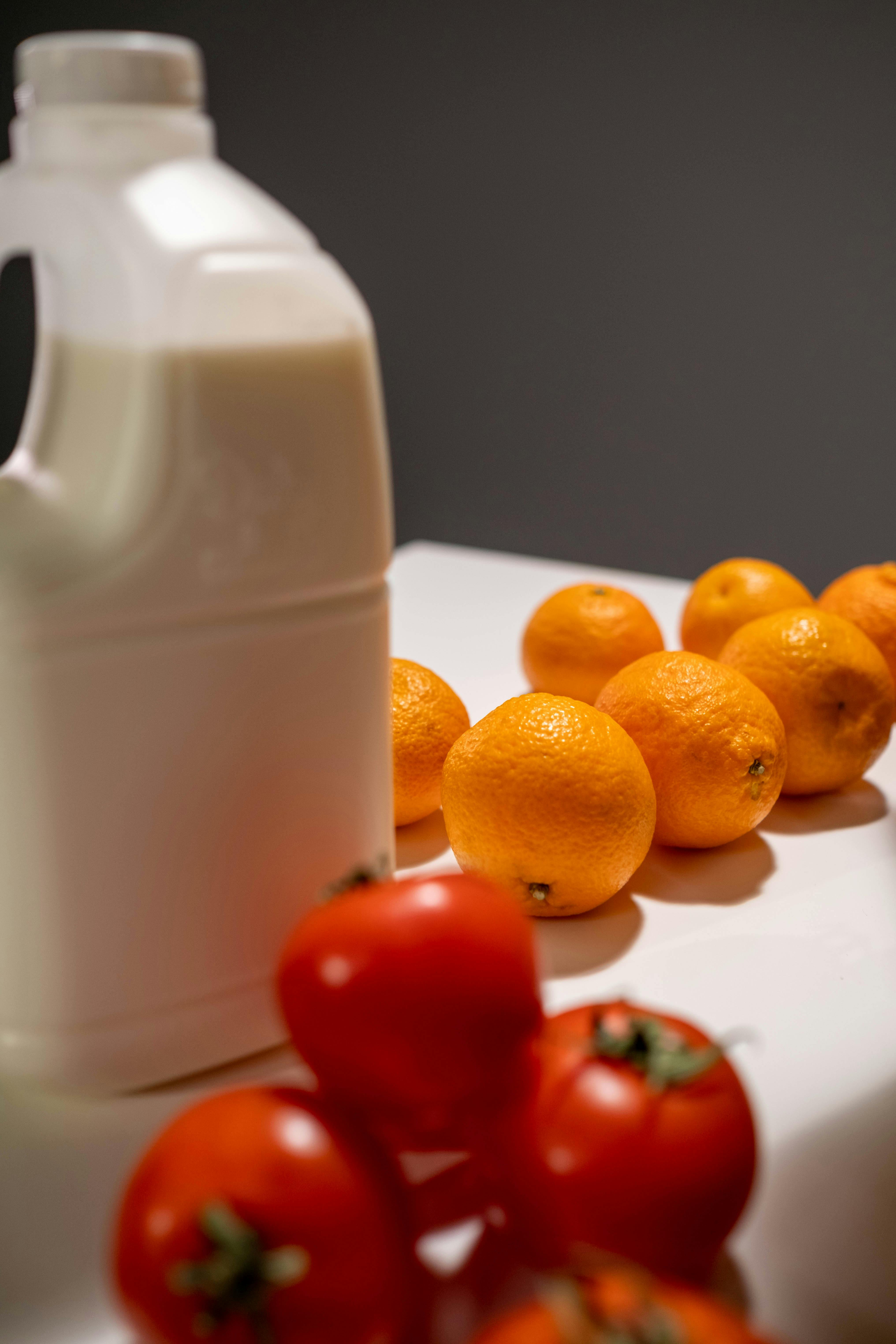 orange fruits beside white plastic pitcher