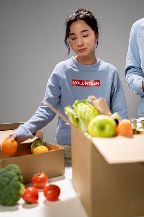 Woman in Blue Sweater Holding Orange Fruit