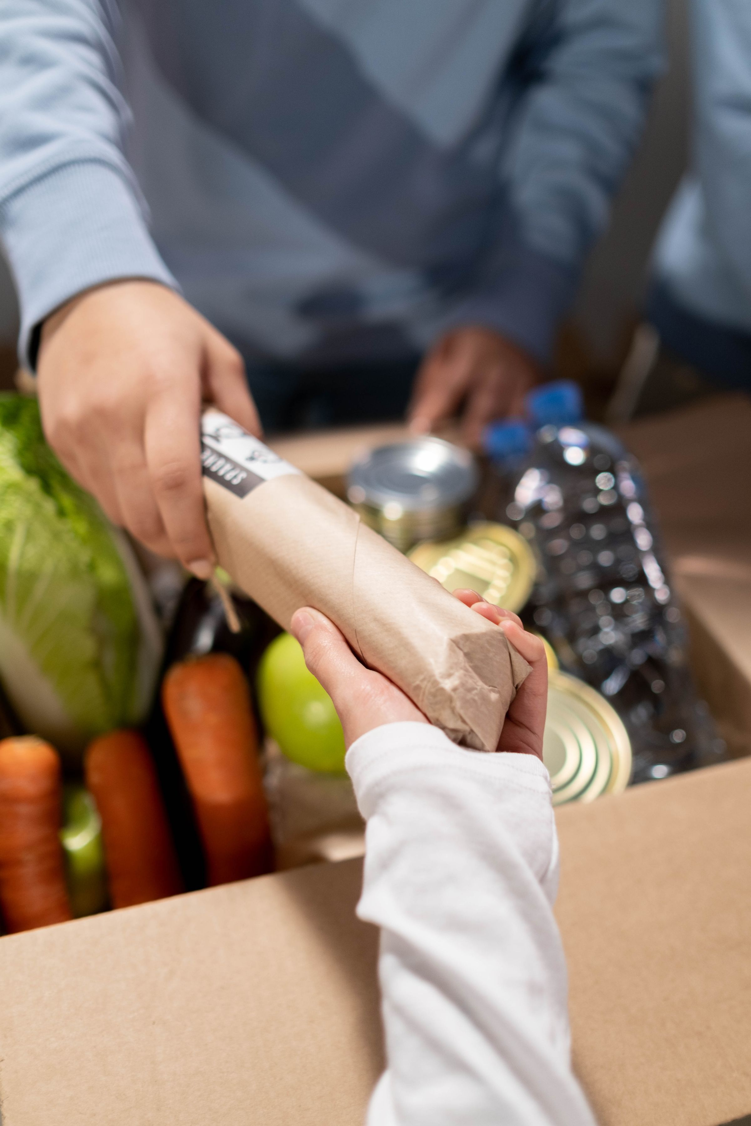 Volunteers handing a box of essential groceries to a community member.