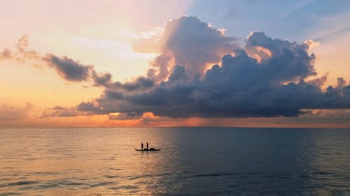 Silhouette of Person Standing on Boat in the Ocean