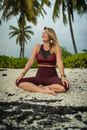Cheerful woman sitting on beach with lotus pose