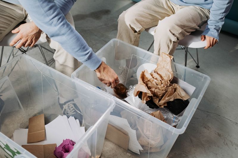 Hands sorting recyclables into color-coded bins