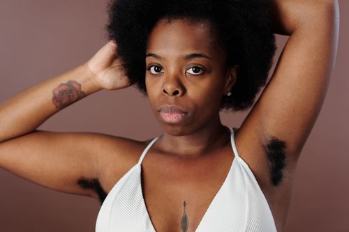 Free Close-up portrait of a confident woman with raised arms and natural beauty, embracing body positivity. Stock Photo