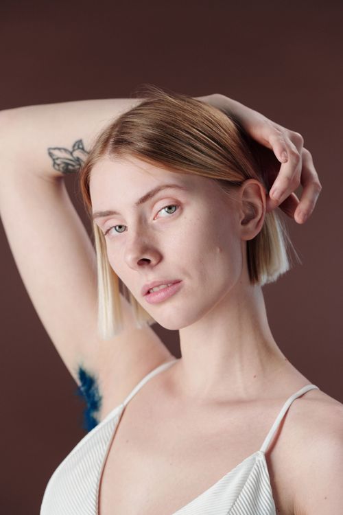 Free Studio portrait of a young woman with raised arm and tattoo, displaying confidence and individuality. Stock Photo