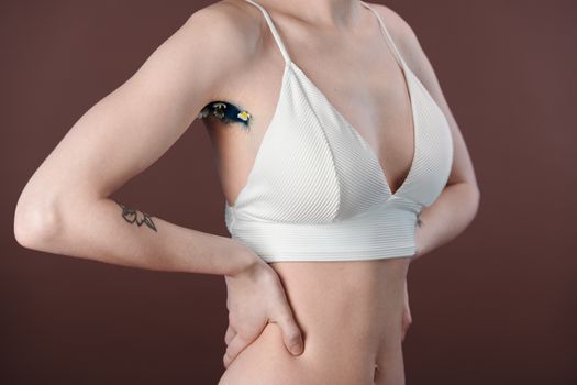 Artistic close-up of a woman's underarm with floral design, wearing a white crop top.