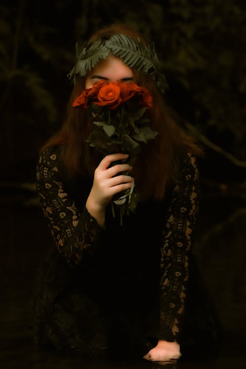 Free A Woman Covering Her Face with Red Roses Stock Photo