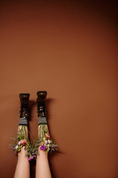 Artistic shot of legs wearing boots with floral socks on a brown backdrop.