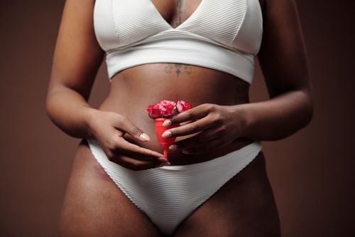 Free Close-up of woman holding menstrual cup with flowers, promoting feminine health. Stock Photo