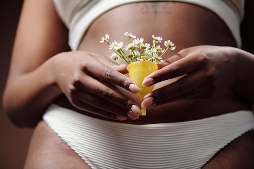 Free Close-up of a woman's hands holding a menstrual cup filled with flowers, symbolizing femininity and care. Stock Photo