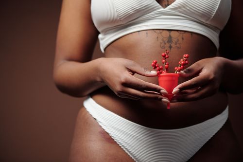 Free A close-up shot of a woman in white underwear holding a red menstrual cup decorated with berries. Stock Photo