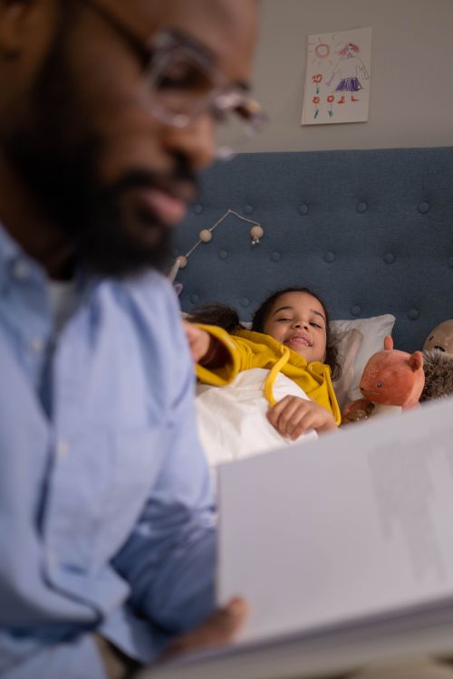 Free A father reads a bedtime story to his daughter, creating a warm and loving atmosphere. Stock Photo