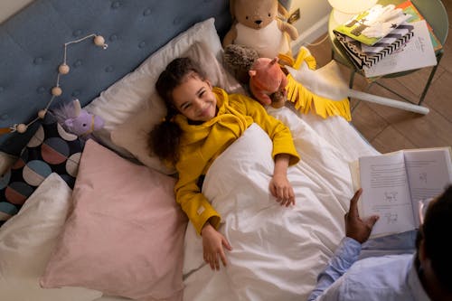 Free Overhead Shot of a Girl Smiling while Listening to a Bedtime Story Stock Photo