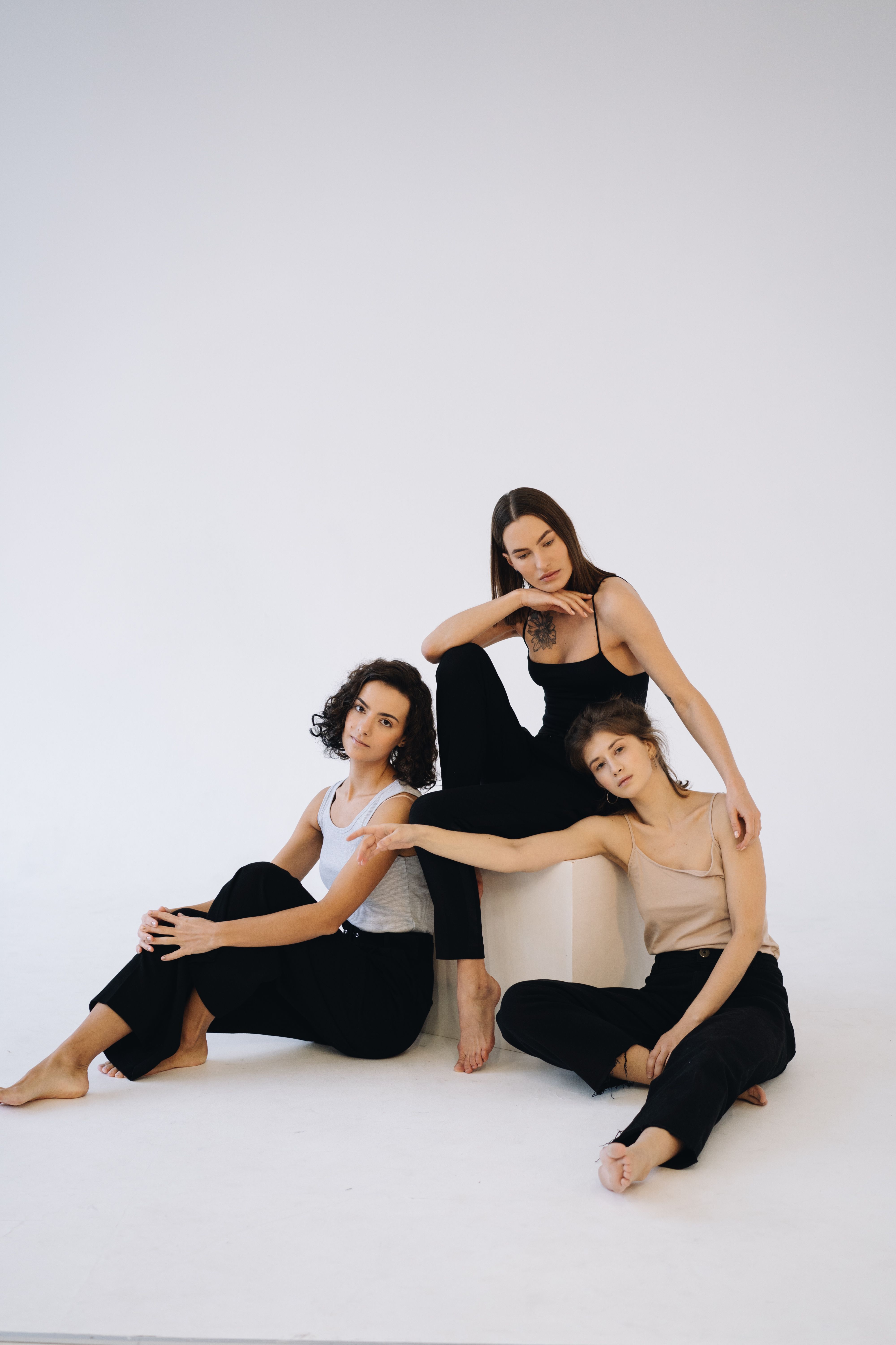 Three women posing gracefully in a minimalist studio setting.