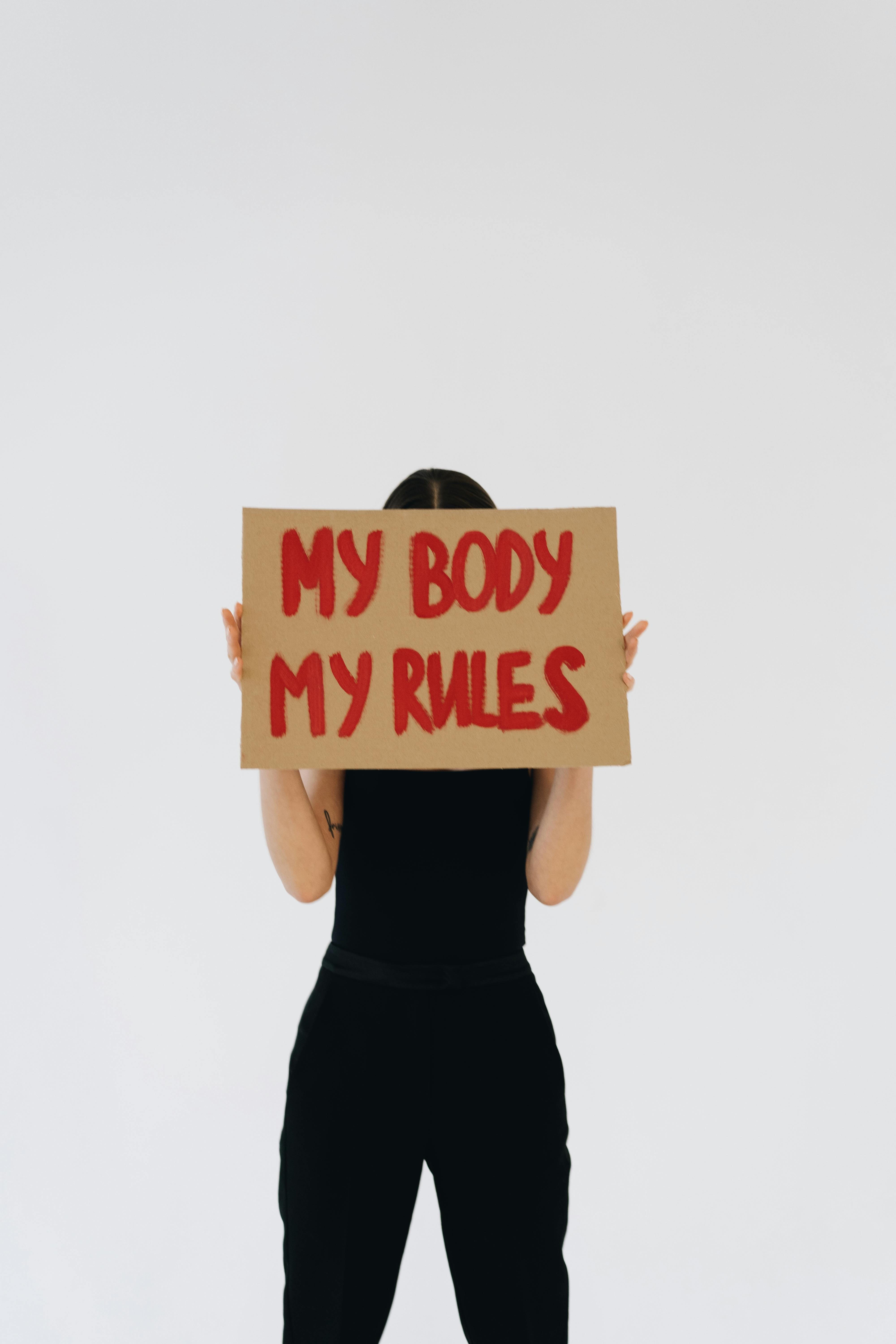 a person in black outfit holding carboard with message