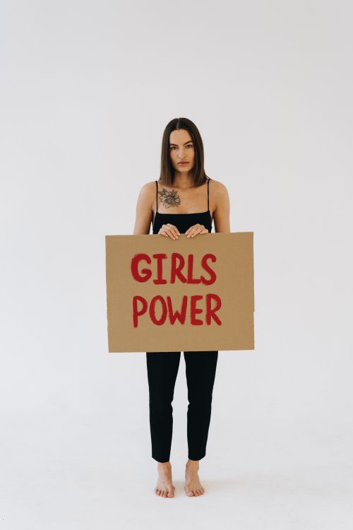 Free Woman standing barefoot holding a 'Girls Power' sign, symbolizing empowerment and feminism. Stock Photo