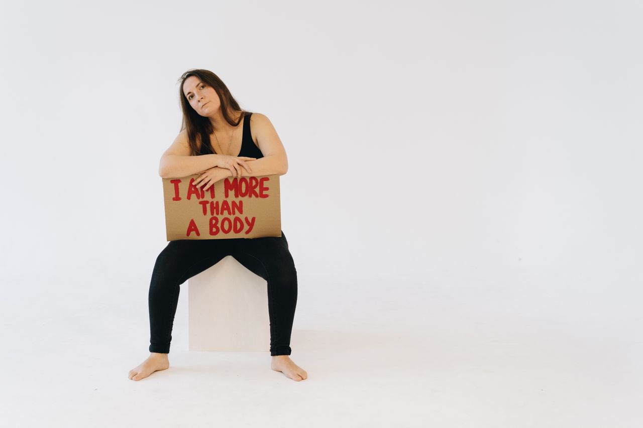 woman holding i am more than a body sign promoting empowerment and equ
