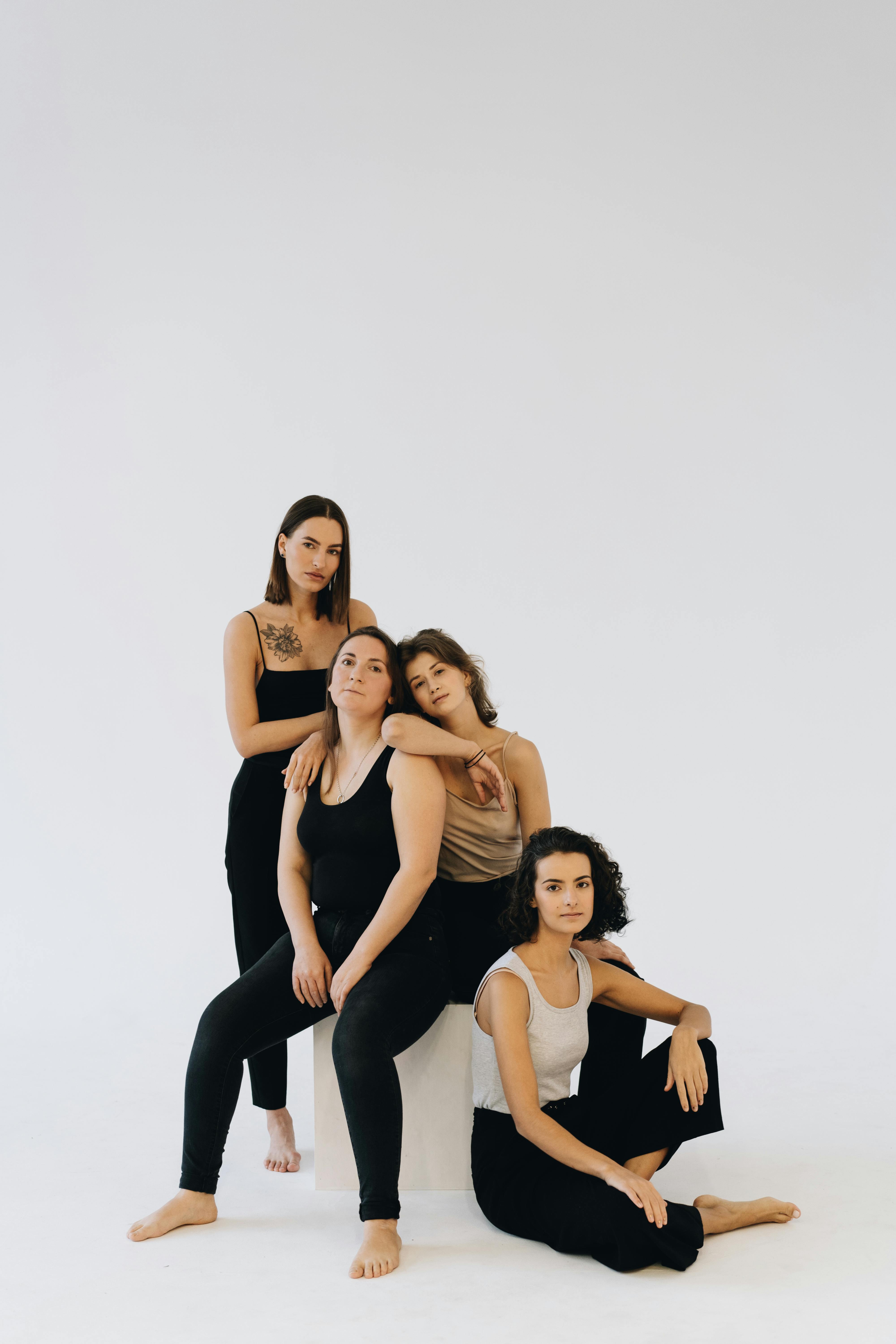 四位多元化的女性在极简主义工作室环境中一起摆姿势，展示团结和多样性