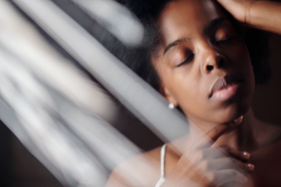 A woman with her eyes closed in soft striped light
