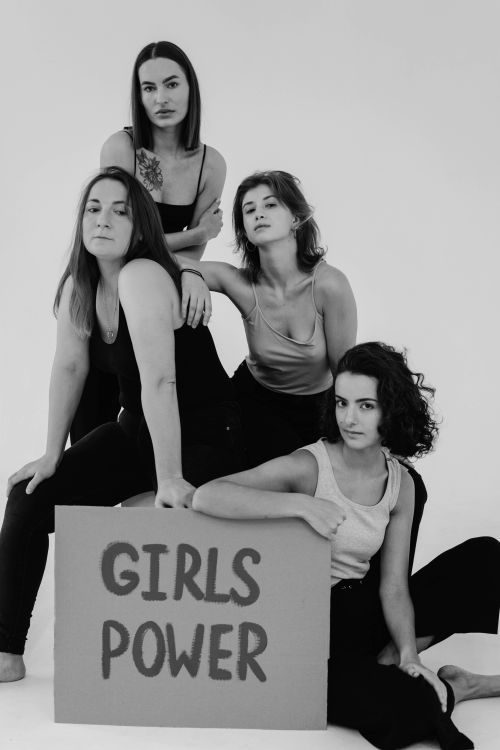 Free Black and white studio shot of diverse women posing with a 'Girls Power' sign, celebrating feminism and friendship. Stock Photo